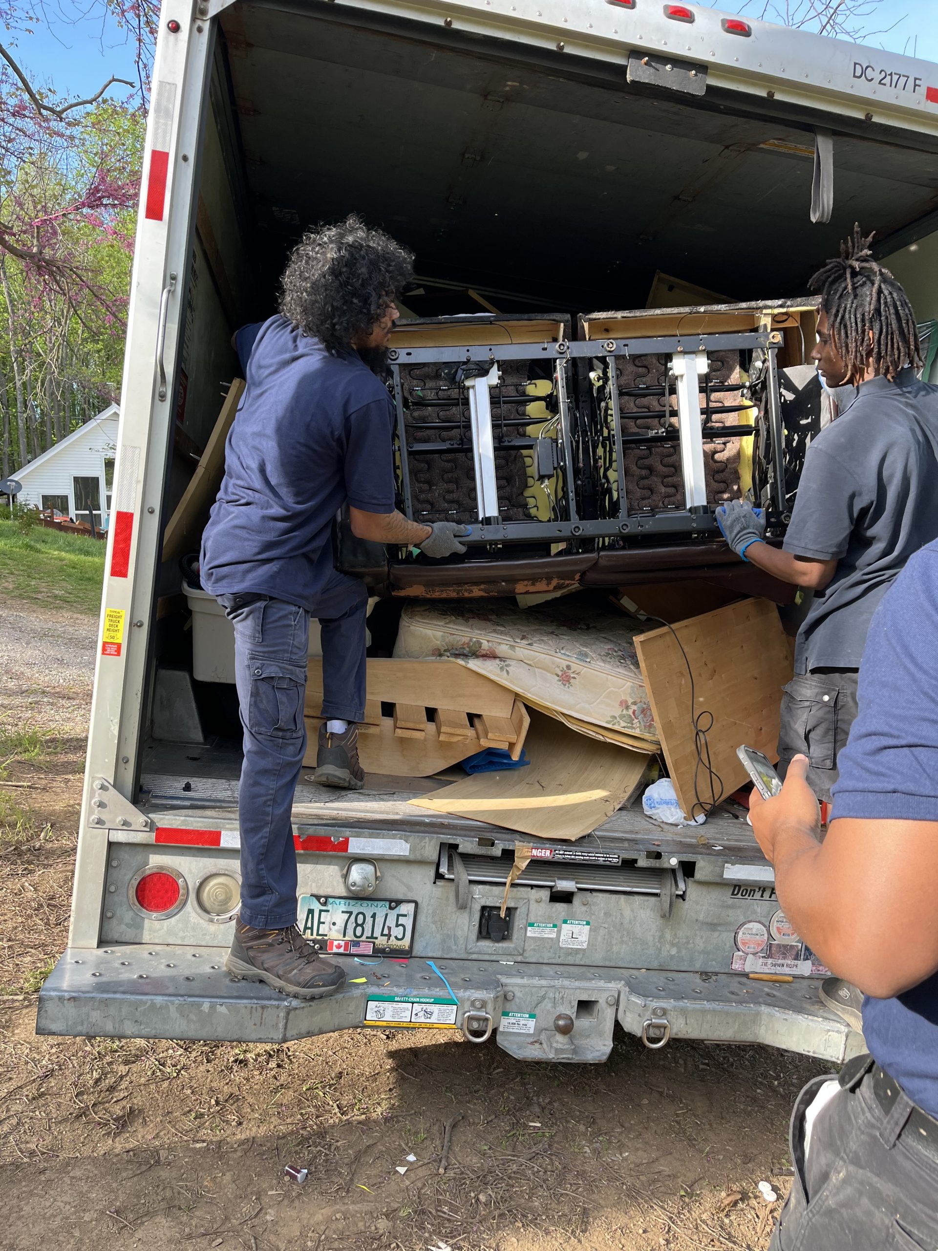 Junk removal Rockville, MD — Buk'em Hauling & Junk Removal Buk'em Hauling crew loading furniture into a junk removal truck in Rockville, MD