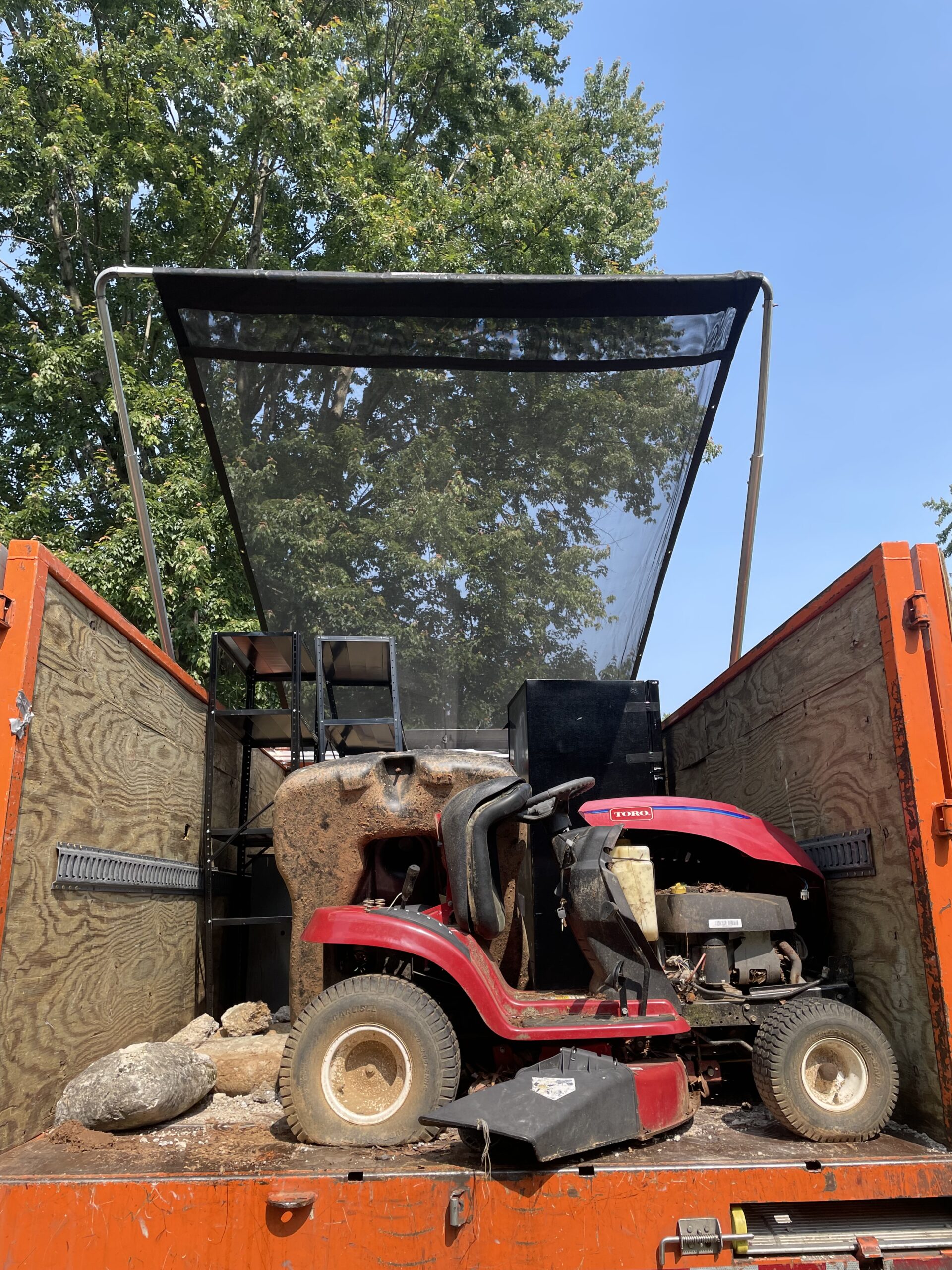 Riding mower and appliance junk removal in an orange hauling truck Riding mower and appliance junk removal in an orange hauling truck